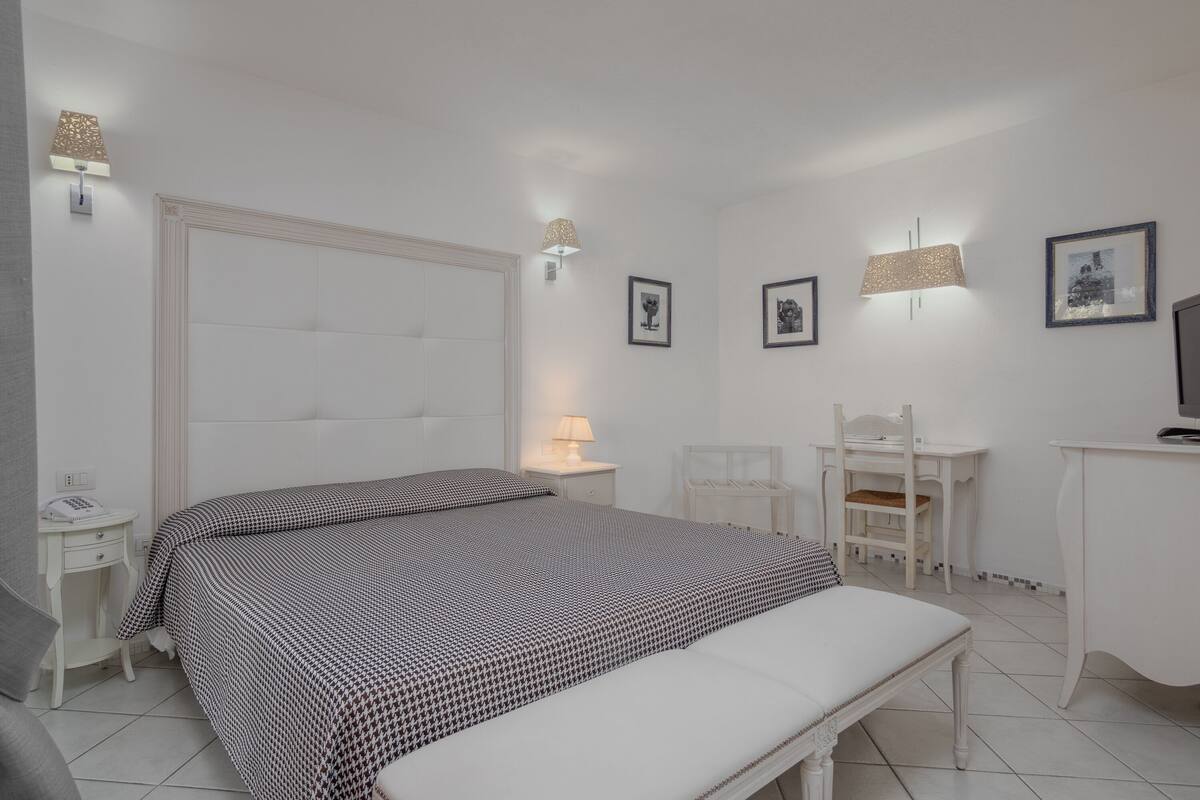 Un dormitorio con una cama grande, mesitas de noche, un escritorio y sillas.