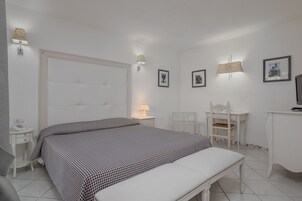 Un dormitorio con una cama grande, mesitas de noche, un escritorio y sillas.