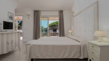 Ein Schlafzimmer mit Bett, Nachttisch, Lampe, Fernseher und Blick ins Freie.