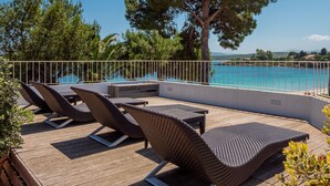 A wooden deck with wicker lounge chairs and a view of a turquoise sea. - The Pelican Beach Resort & SPA - Adults Only (Olbia)