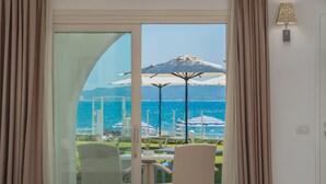 A hotel room with a sliding glass door leading to a balcony with outdoor seating and umbrellas. - The Pelican Beach Resort & SPA - Adults Only (Olbia)