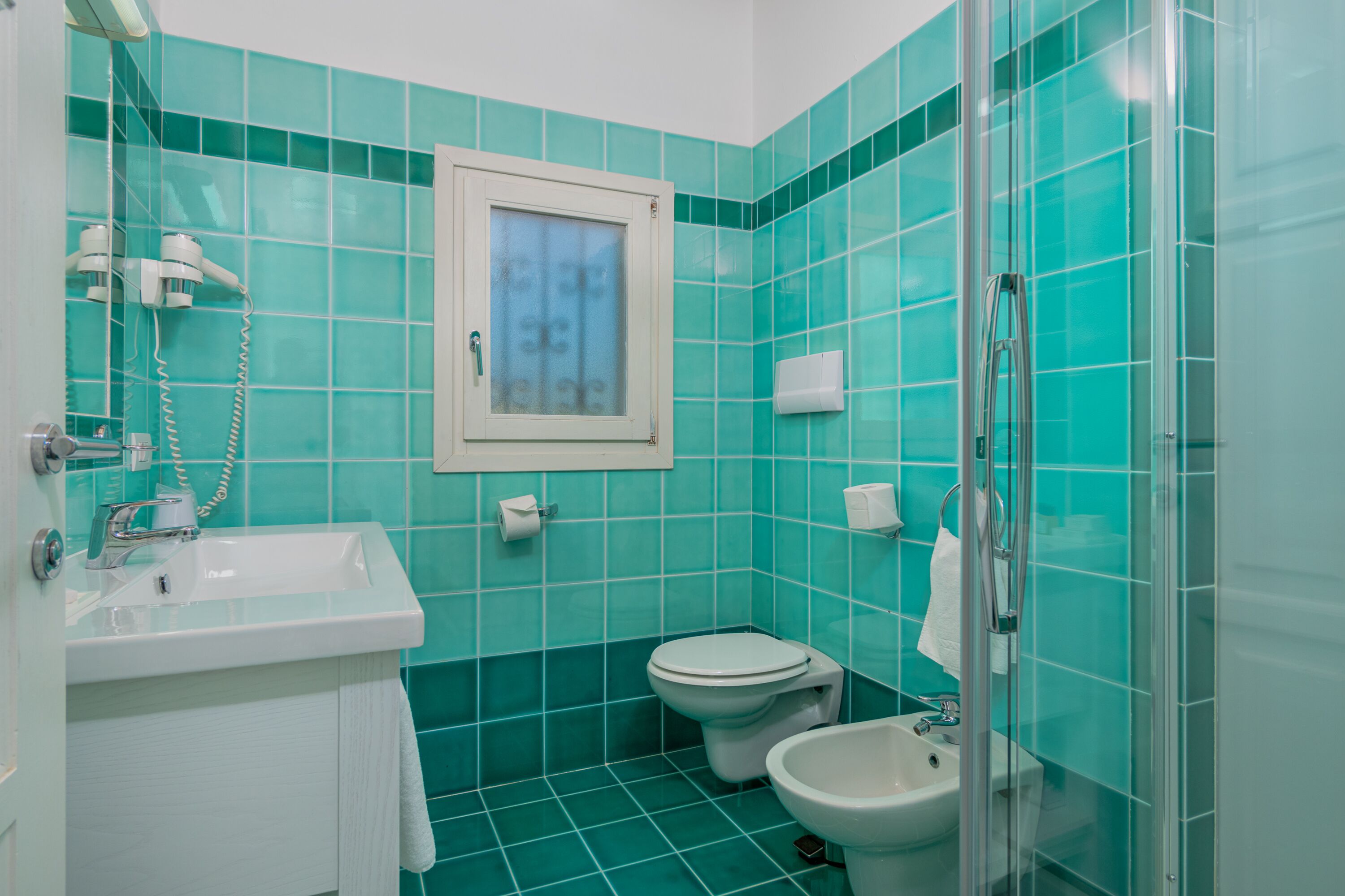 A bathroom with a sink, toilet, bidet, and glass shower enclosure.