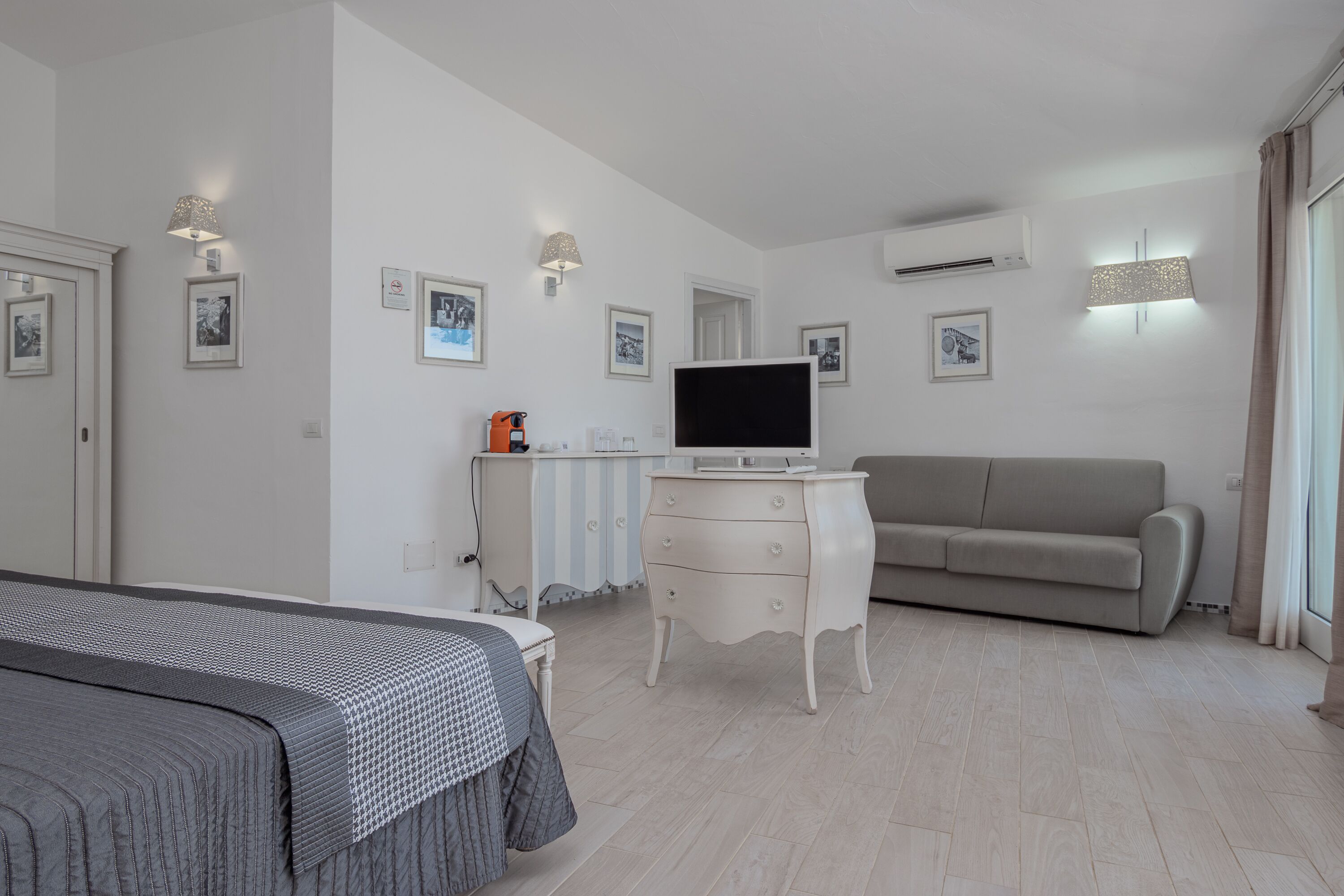 Ein modernes Schlafzimmer mit einem Bett, einem Fernseher, einer Kommode und einem Sofa.