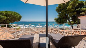 A terrace with wicker furniture, a large umbrella, and a view of the sea. - The Pelican Beach Resort & SPA - Adults Only (Olbia)