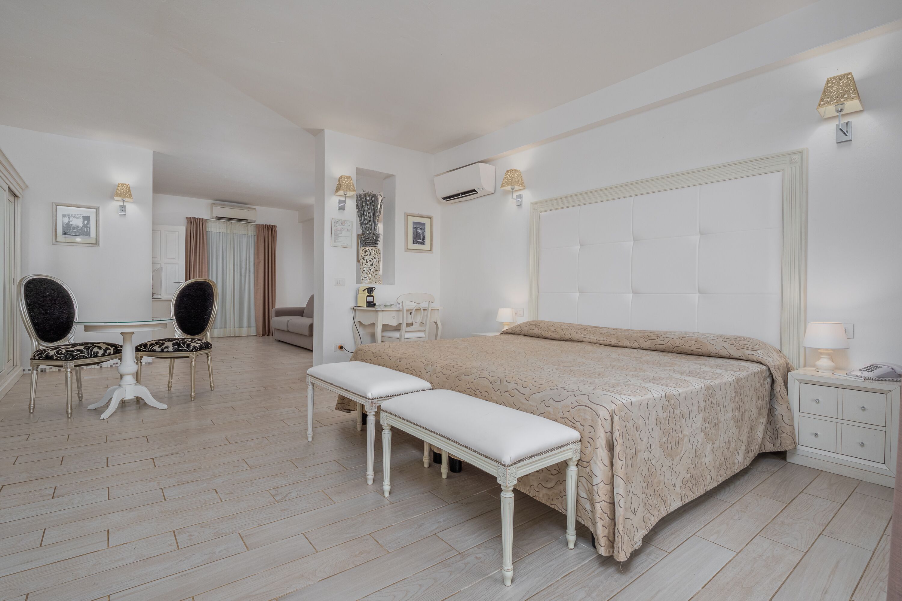 A bedroom with a large bed, a bedside table, a chair, and a small table with a lamp.