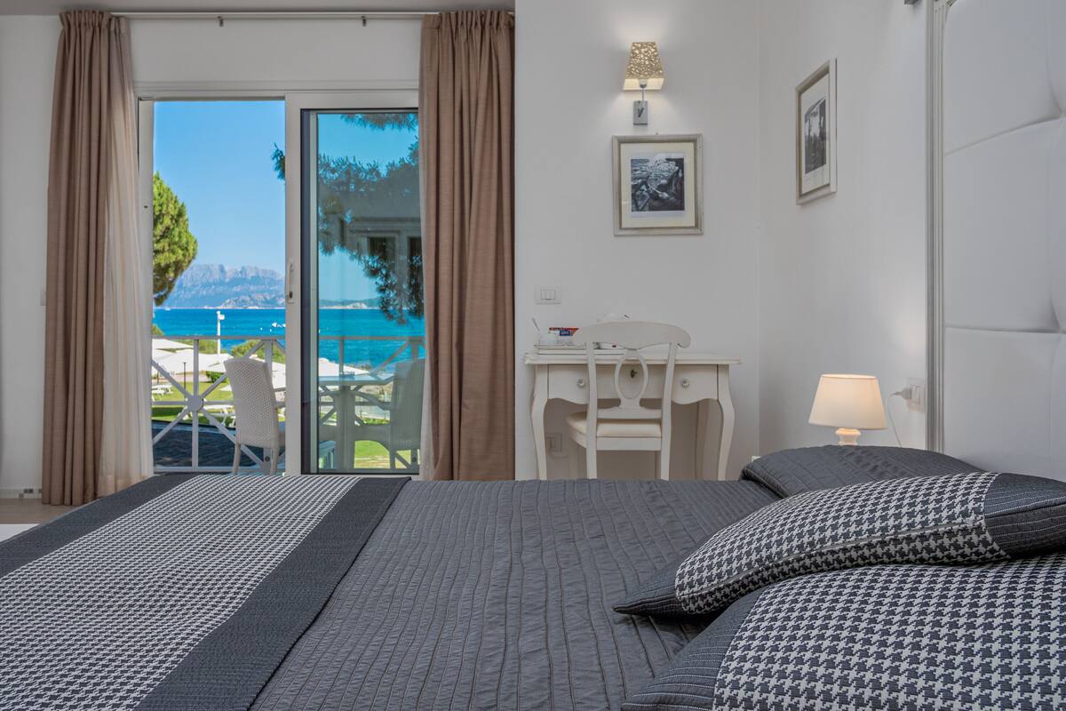 Habitación de hotel con cama, escritorio, una silla y vistas al mar.