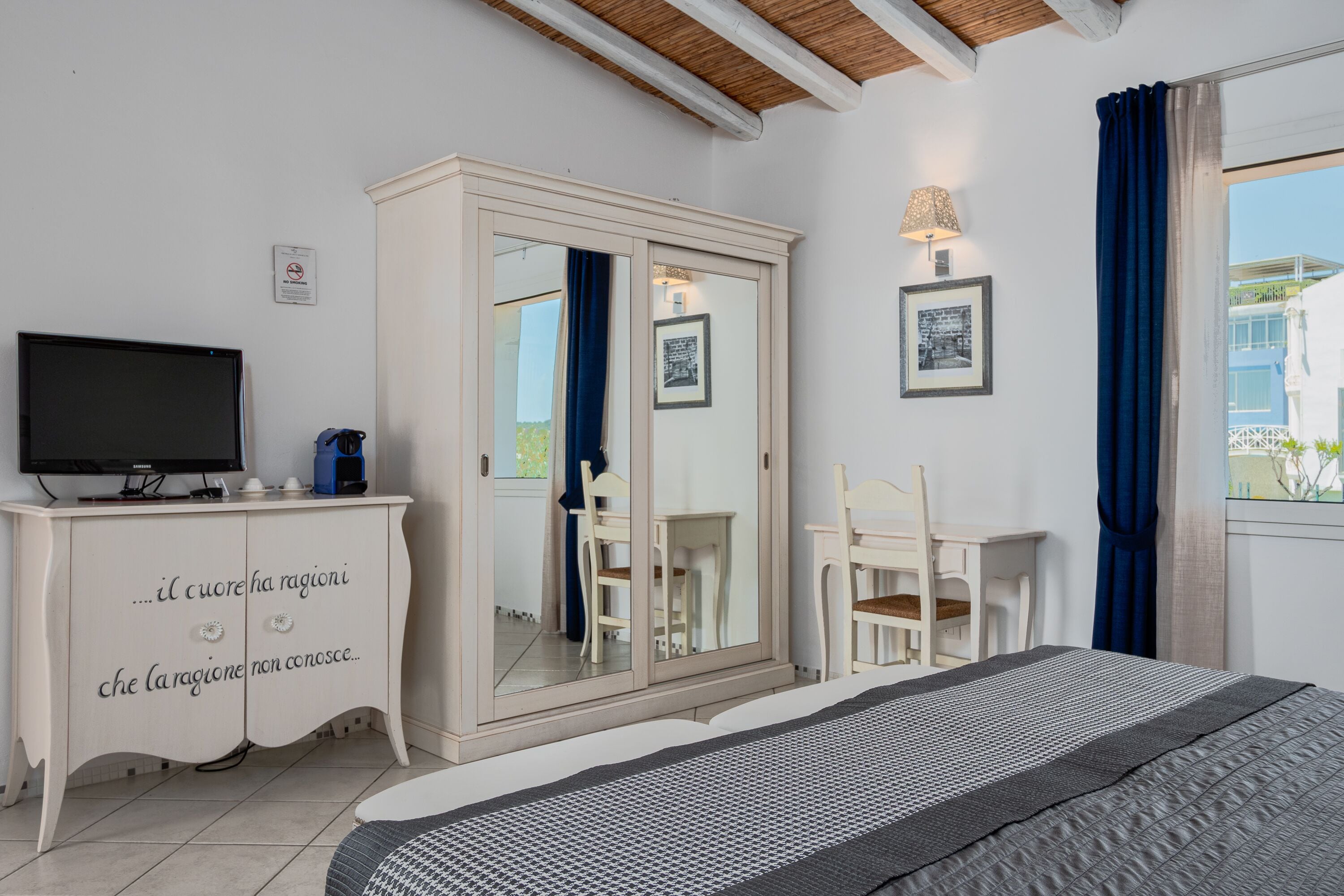Un dormitorio con cama, televisor, armario, escritorio y silla.