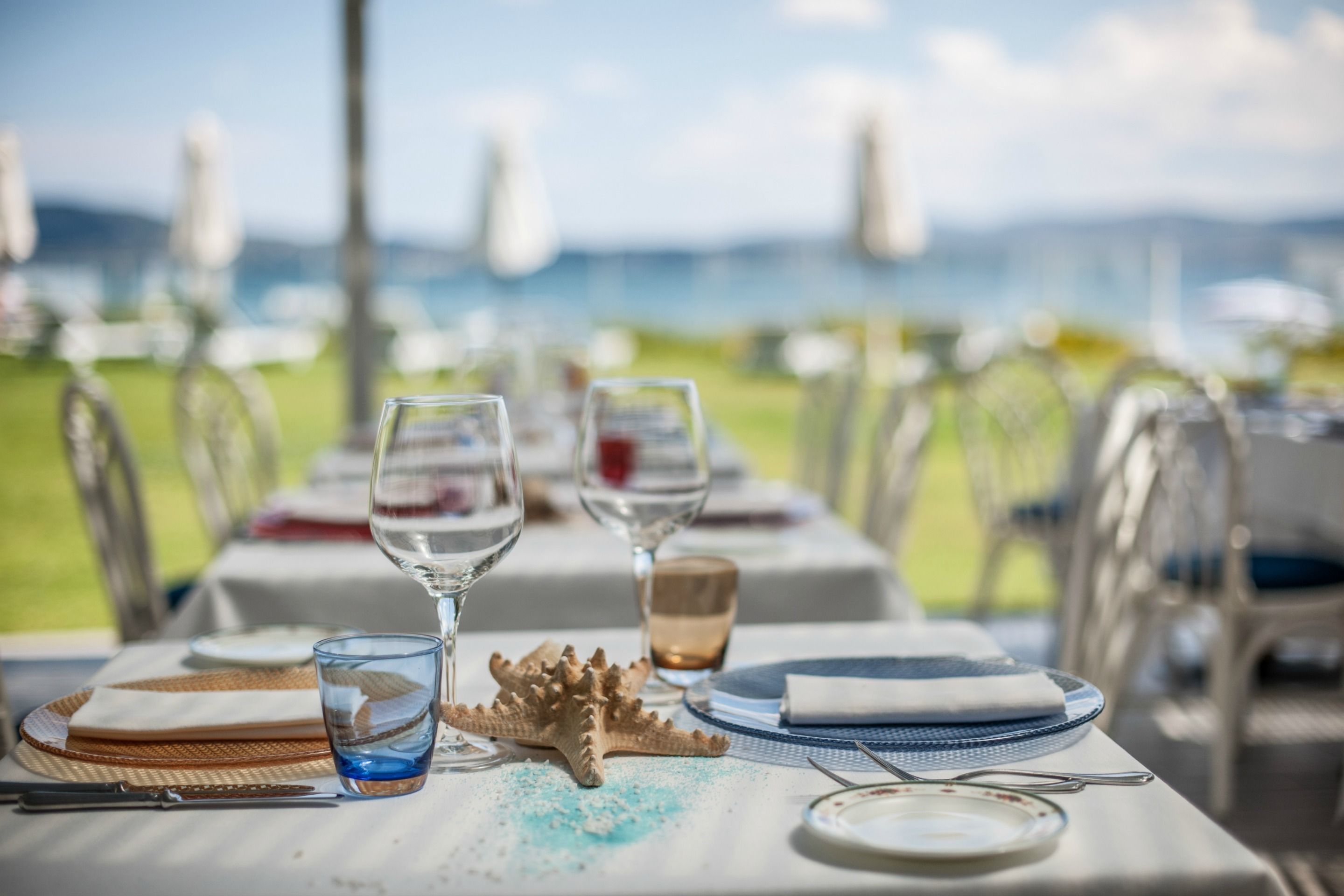 A table set for dining with clear glassware, plates, and a starfish decoration, overlooking a scenic view.