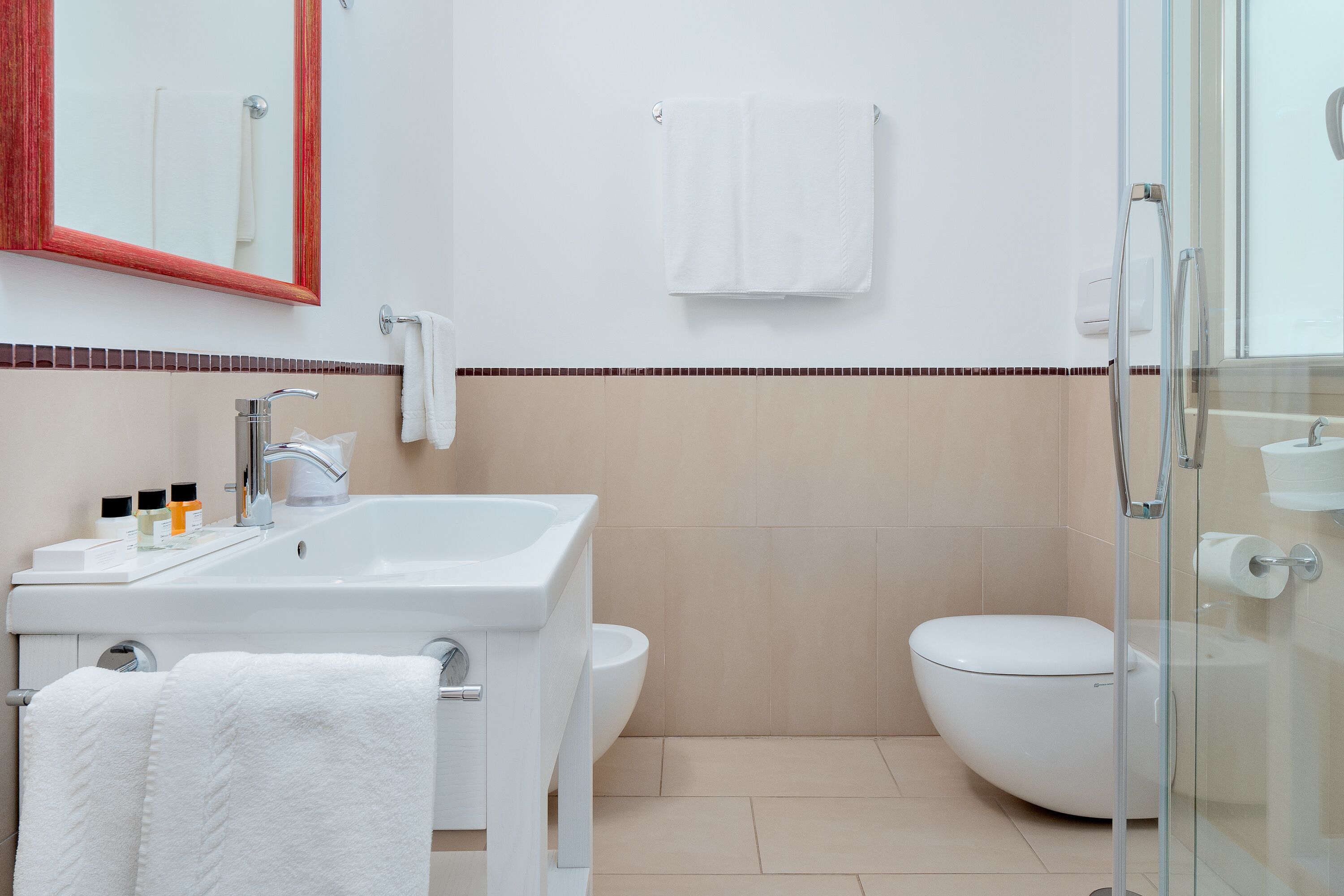 Ein modernes Badezimmer mit Waschbecken, Spiegel, Toilette und Duschkabine aus Glas.