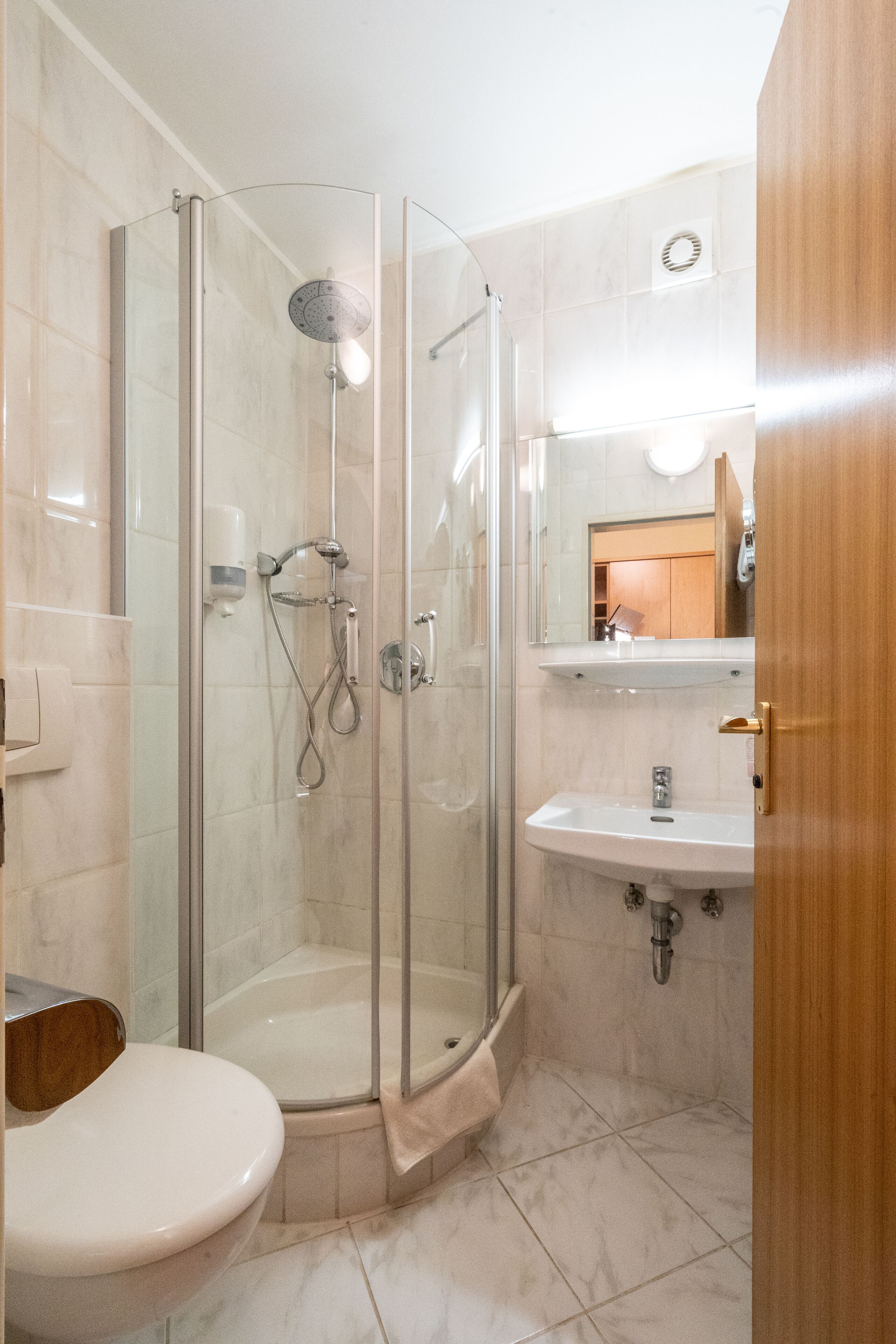 A modern bathroom with a glass-enclosed shower, a white sink, and a toilet.