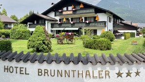 A traditional hotel with a sign reading "Hotel Brunnthal" and a carriage in the courtyard. - Hotel Garni Brunnthaler (Garmisch-Partenkirchen)