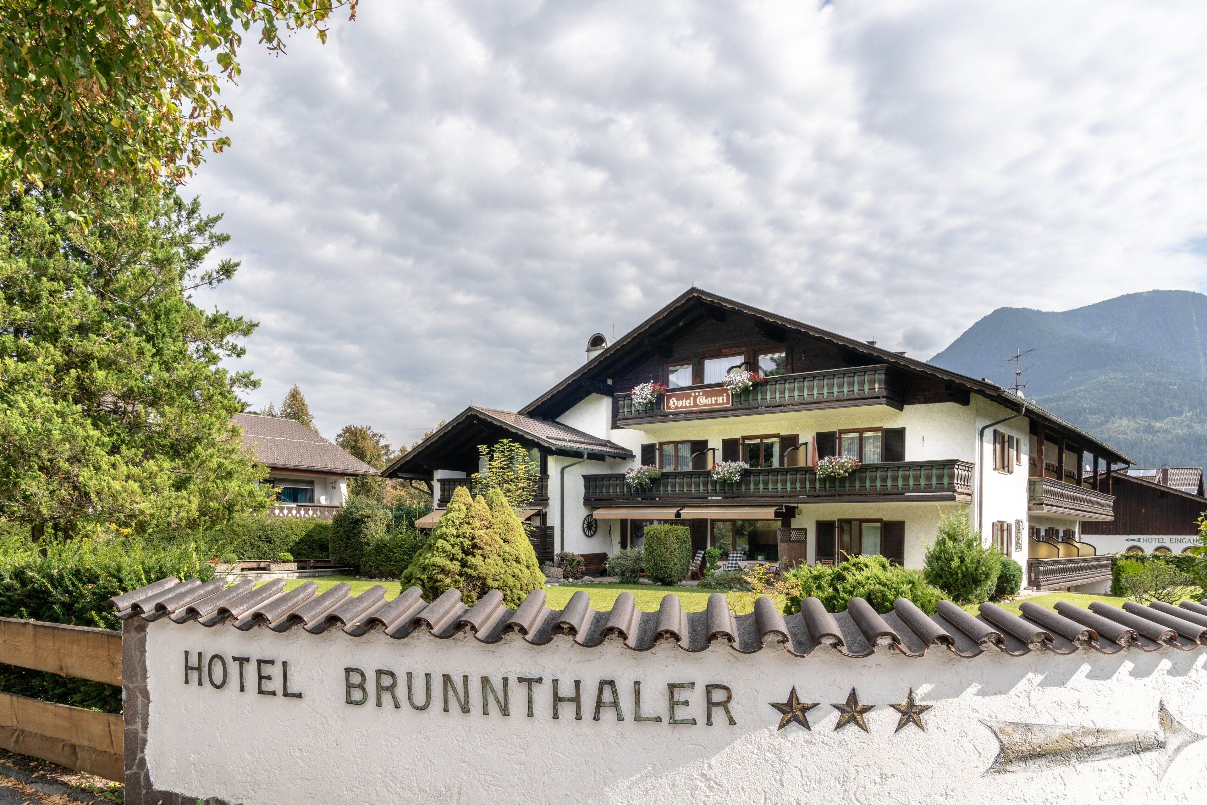 Un hôtel avec une enseigne indiquant « HÔTEL BRUNNTHALER » et une classification de trois étoiles.