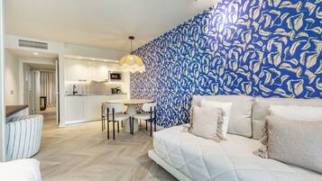 Ein modernes Hotelzimmer mit einem großen Bett, einem Essbereich und einer Küche im Hintergrund.