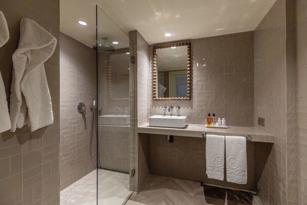 Une salle de bain moderne avec une douche à parois de verre, un meuble-lavabo avec un miroir et un porte-serviettes.