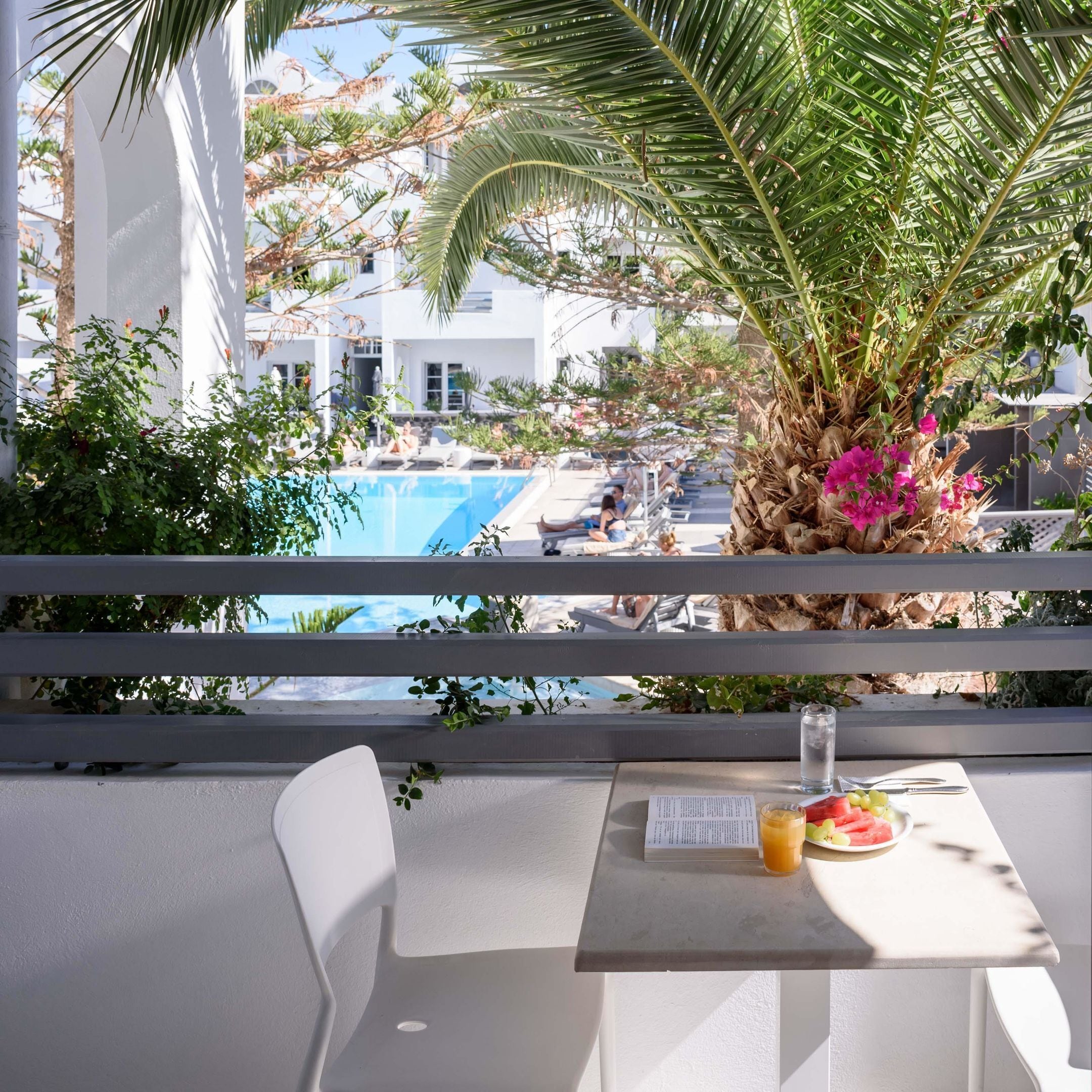 A balcony with a table, a chair, a menu, and a glass of orange juice.