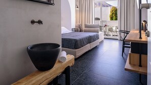Una habitación de hotel moderna con una cama grande, un banco de madera, un cuenco negro y una mesita.