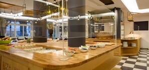Una cocina moderna con encimera de madera, separaciones de vidrio y diversos alimentos a la vista.