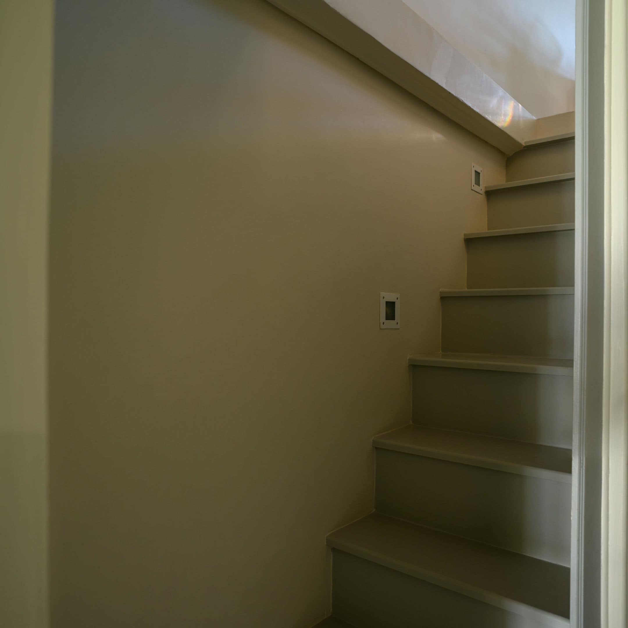 A staircase with beige walls and a light fixture at the top.