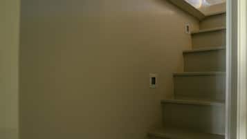 A staircase with beige walls and a light fixture at the top.