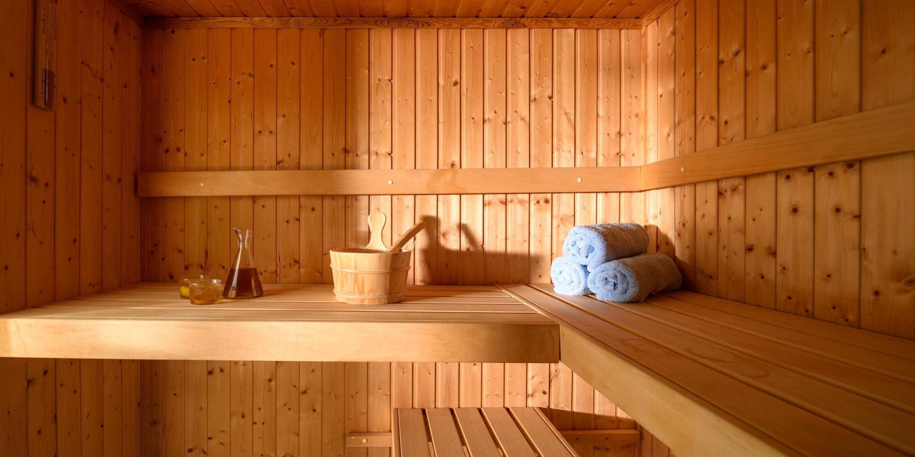 Una sauna de madera con bancos, un cubo y toallas.