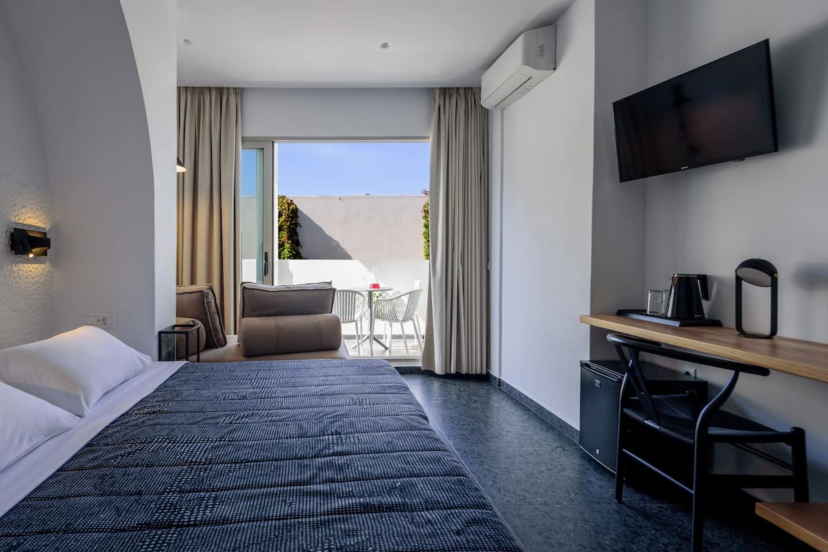 Une chambre d’hôtel équipée d’un lit, d’un bureau, d’une chaise, d’une télévision et offrant une vue sur l’extérieur.