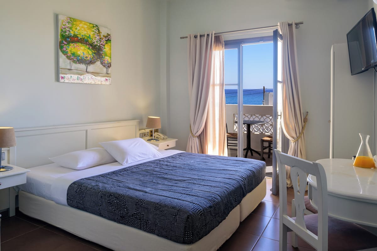 Une chambre d’hôtel avec un lit, un bureau, une chaise, une télévision et un tableau au mur.