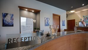 A reception area with a sign labeled "RECEPTION," a glass vase with lights, and artwork on the walls. - Medea (Alba)