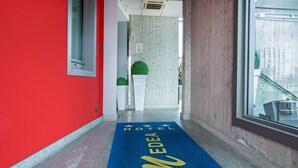 A hotel corridor with a blue carpet marked "EDEA HOTEL" and a red wall. - Medea (Alba)