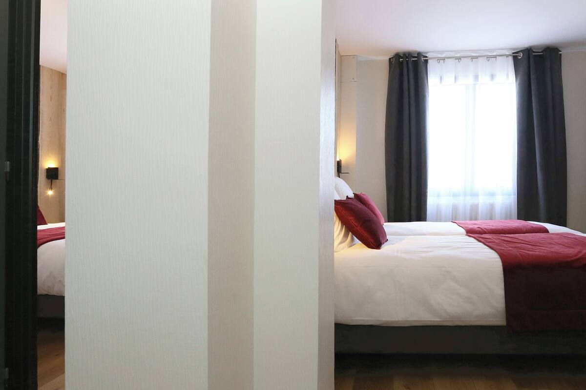 A bedroom with a bed, a nightstand, a lamp, and a window with curtains.