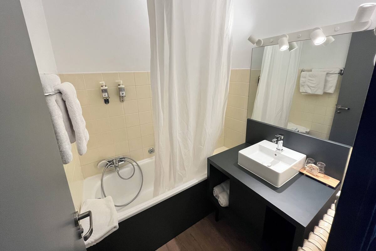 A modern bathroom with a bathtub, a sink, and a mirror.