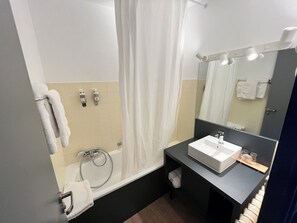 A modern bathroom with a bathtub, a sink, and a mirror.