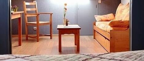 A small, cozy room with a wooden bed, a desk, and a chair.