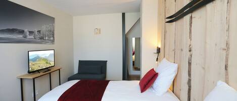 Ein Hotelzimmer mit zwei Betten, einem Fernseher auf einem kleinen Tisch und einem Bild an der Wand.