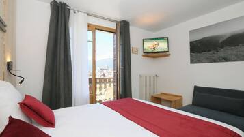 Une chambre d’hôtel avec un lit, une télévision, un canapé, une fenêtre avec des rideaux et une vue sur l’extérieur.