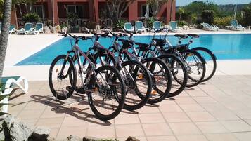 Des vélos sont garés près d’une piscine, avec des chaises longues en arrière-plan.