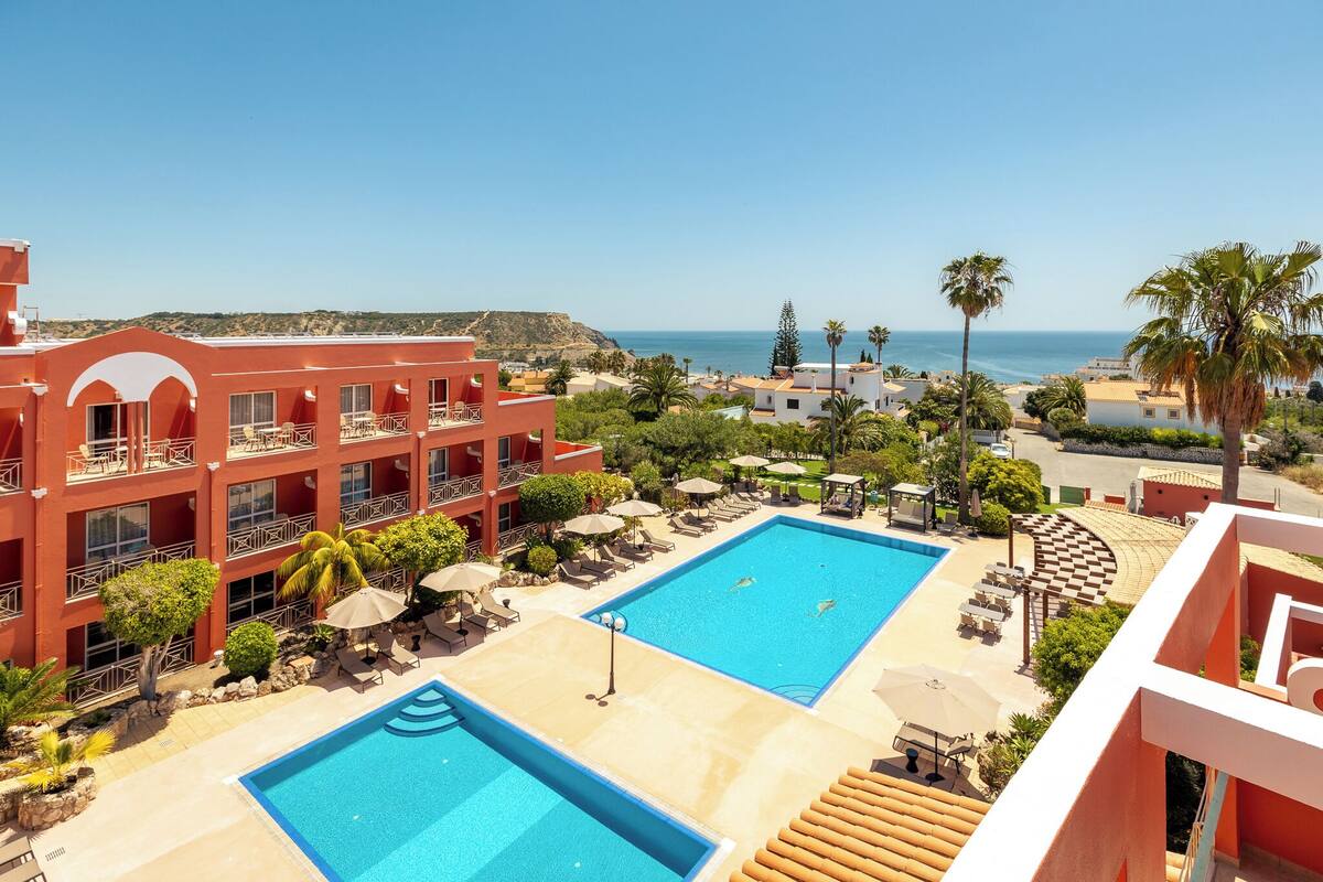 Un hôtel doté d’une piscine, d’un espace extérieur aménagé et offrant une vue sur la mer.