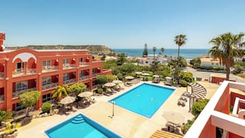 Un hotel con piscina, zona de estar al aire libre y vista al mar.