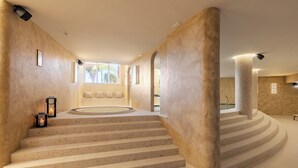 Un interior moderno con una zona de estar circular, una escalera y un ventanal grande.
