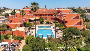 Un resort con piscina central, varios balcones y abundante vegetación.