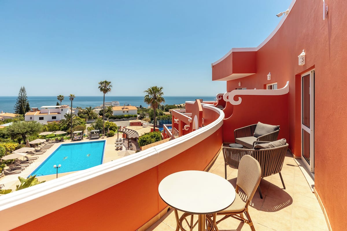 Un balcon avec une piscine, du mobilier d’extérieur et une vue sur la mer et les bâtiments environnants.