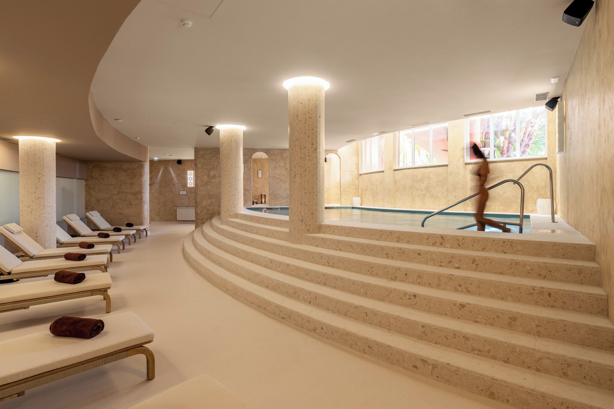 A spa area with a pool, sun loungers, and a staircase leading to the pool.