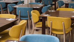 Un salón de conferencias con mesas y sillas, algunas con documentos encima.