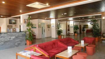 A lobby with red seating, wooden ceiling, and potted plants.