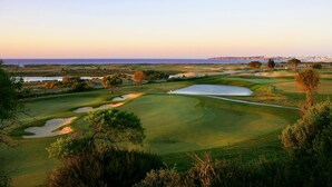 Un campo de golf con búnkeres de arena, un estanque y vistas al océano.
