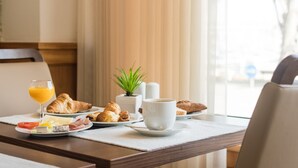 A breakfast table with croissants, a glass of orange juice, a cup, and a small plant.