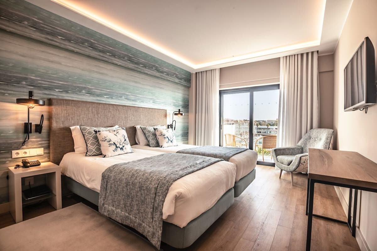 A modern hotel room with a large bed, bedside tables, a desk, and a chair.