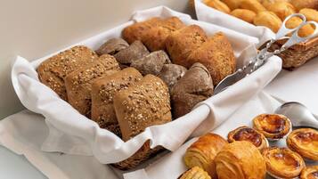 A variety of baked goods including bread, rolls, and pastries arranged on a table.