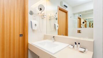 Un baño moderno con un espejo grande, un lavabo y un secador de pelo.