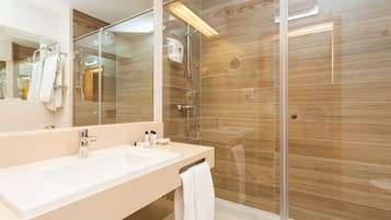 A modern bathroom with a glass-enclosed shower, a large mirror, and a beige vanity.