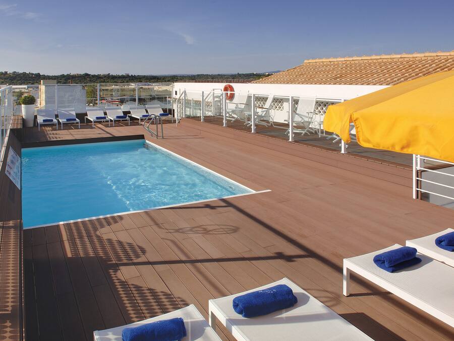 Zona de piscina con tumbonas y un flotador en la cubierta de un crucero.
